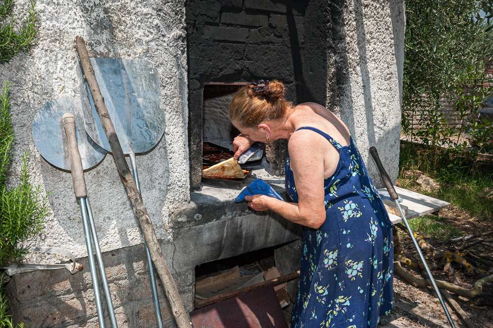 Woman cooking pizza in an outdoor oven
